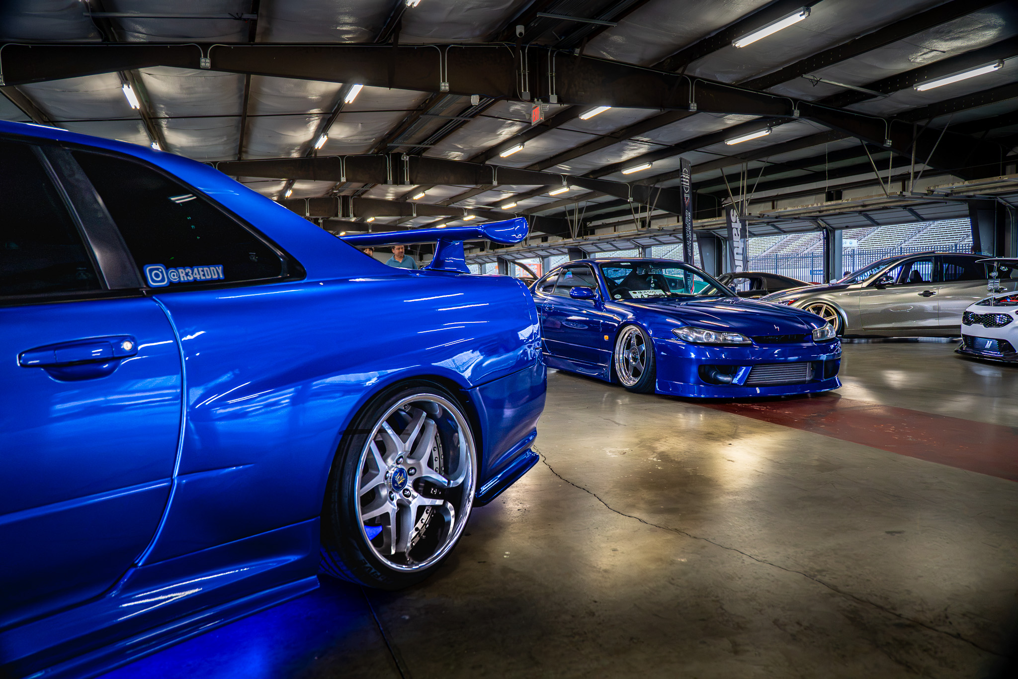 Blue Nissan Skyline and Silvia inside an indoor car show garage