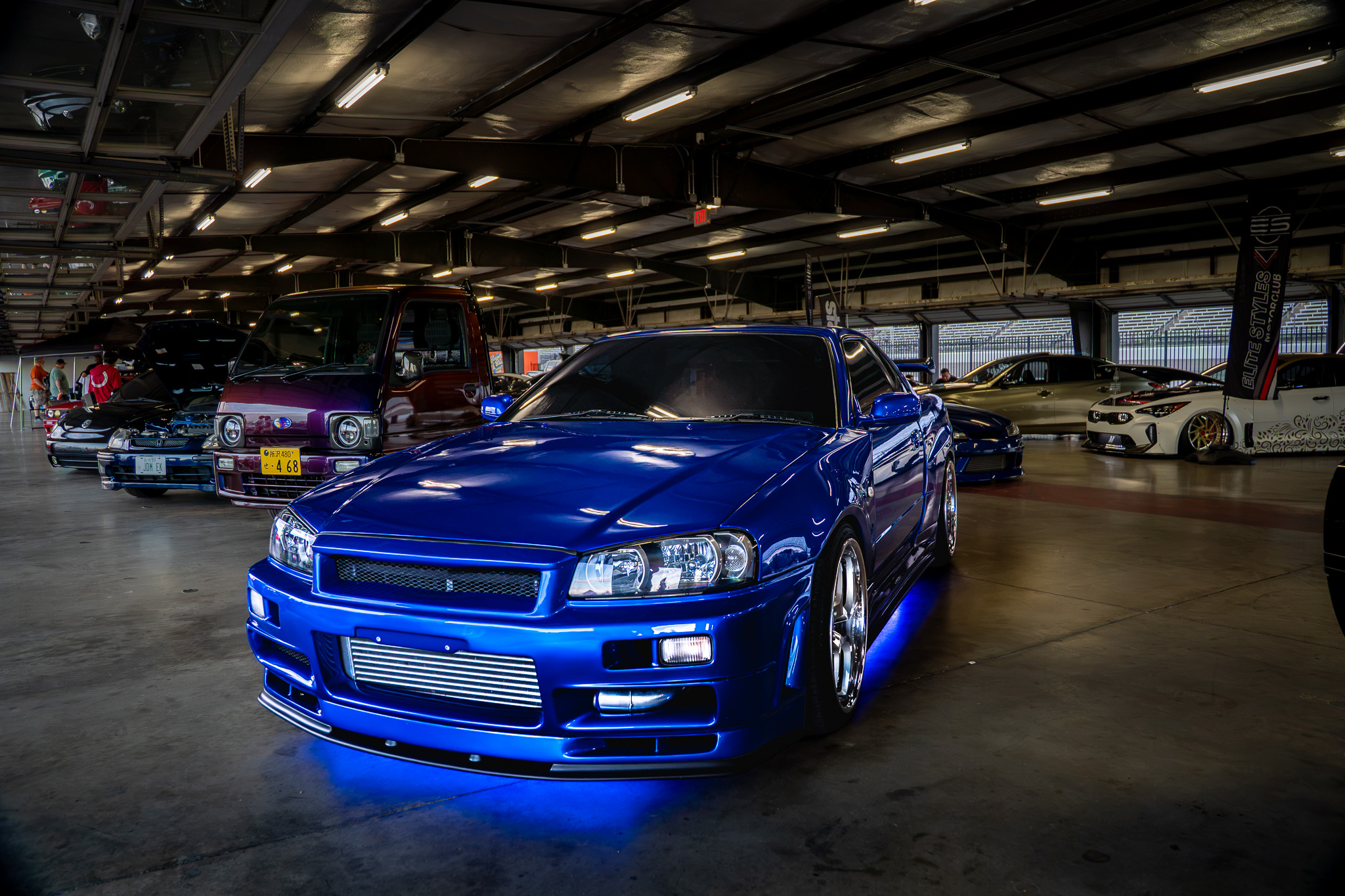 Blue Nissan Skyline GT-R with underglow at an indoor car show