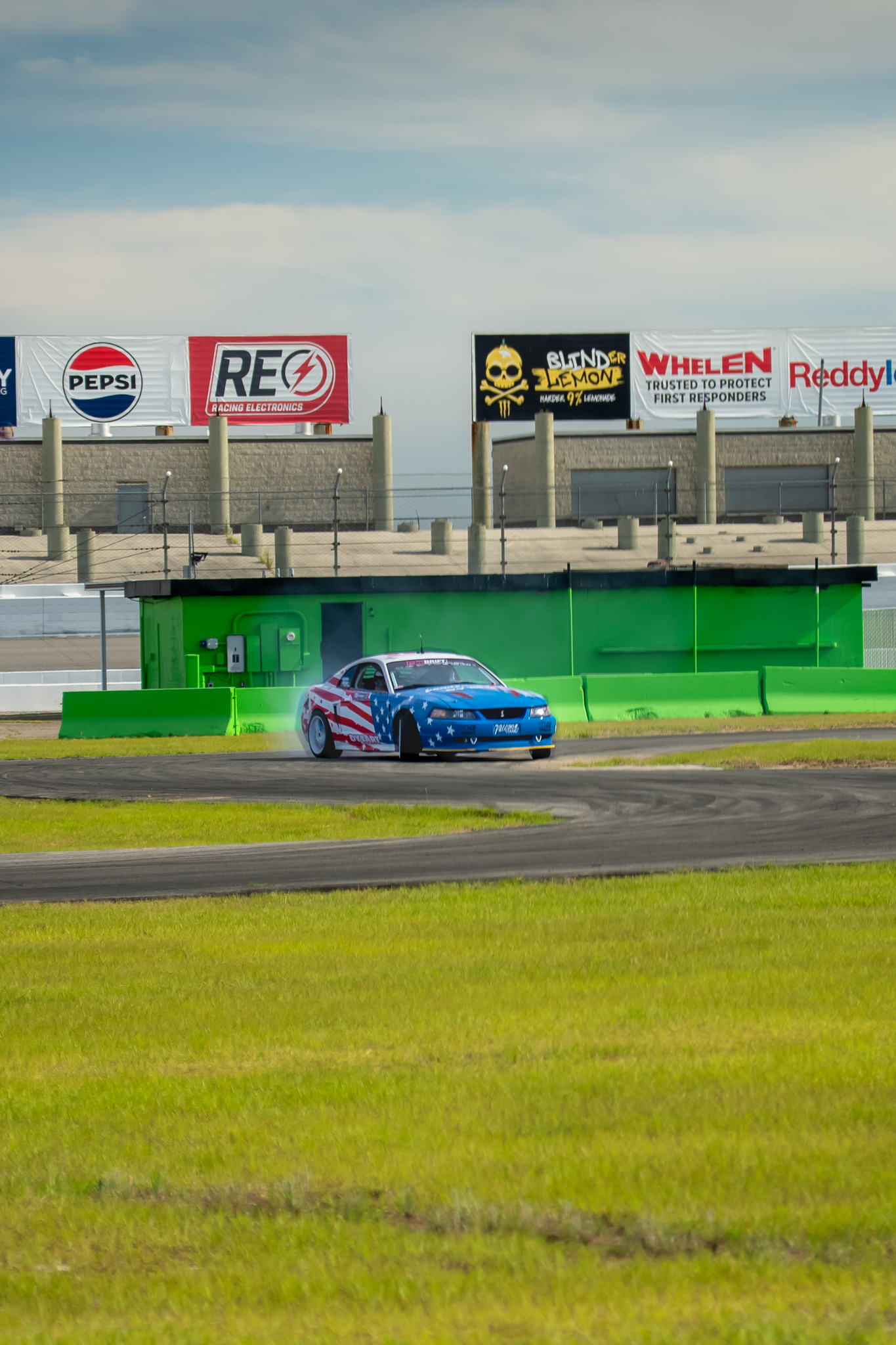 American flag-wrapped Mustang drifting on a race track