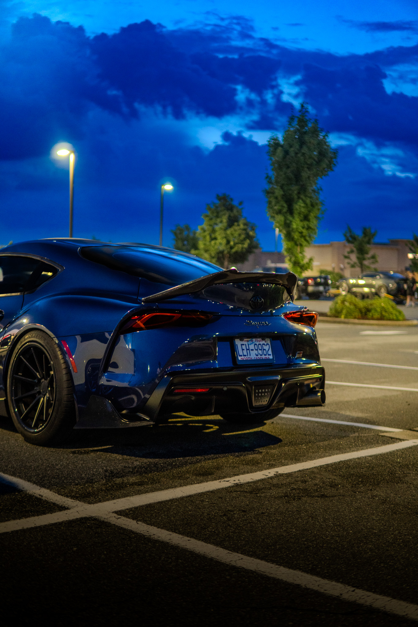 Blue Toyota Supra at dusk under a dramatic sky
