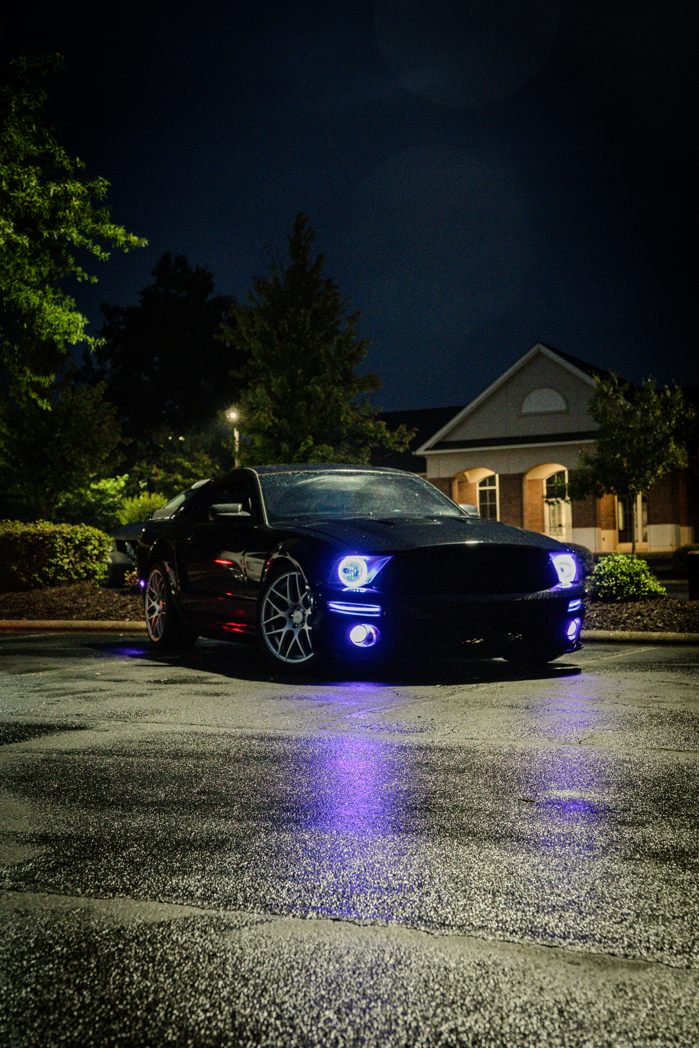 Black Mustang at night with glowing blue LED headlights
