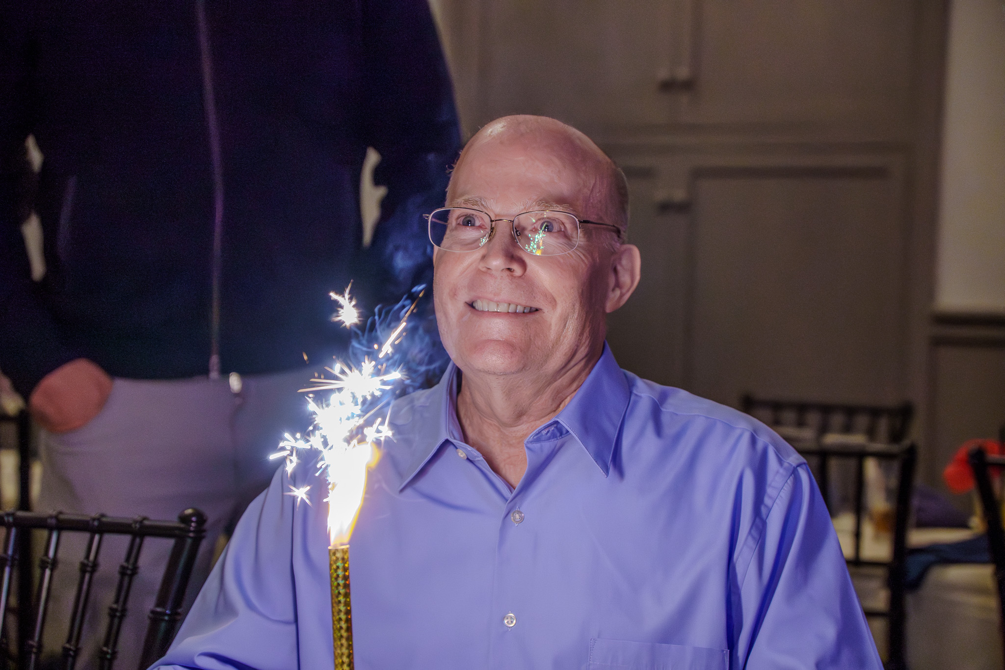 Retirement celebration guest smiling with a lit sparkler
