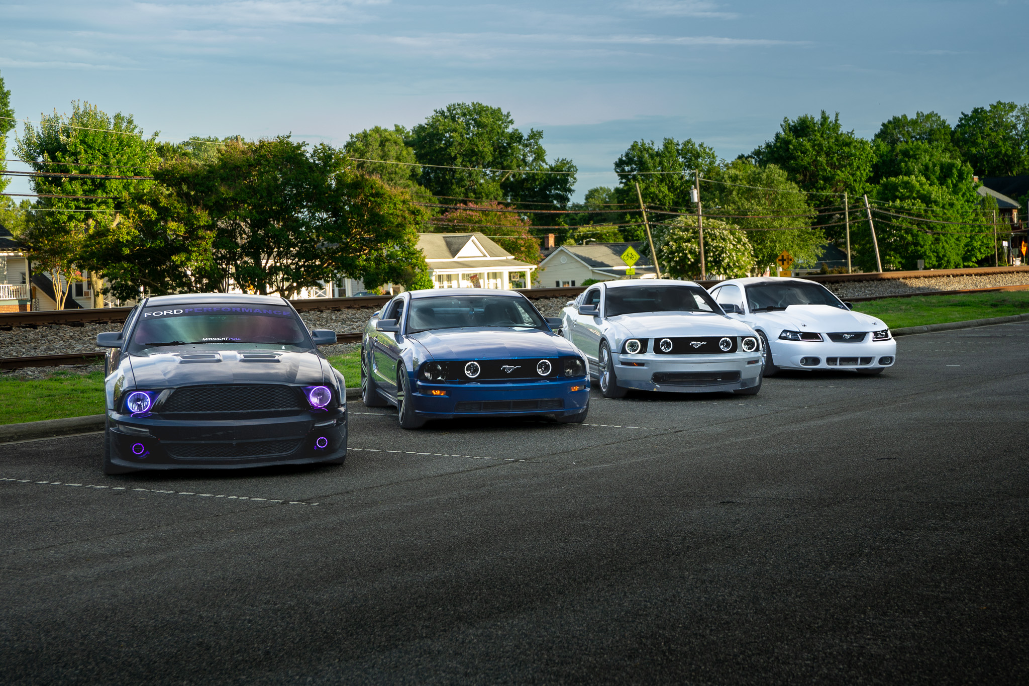 Four modified Ford Mustangs lined up at evening