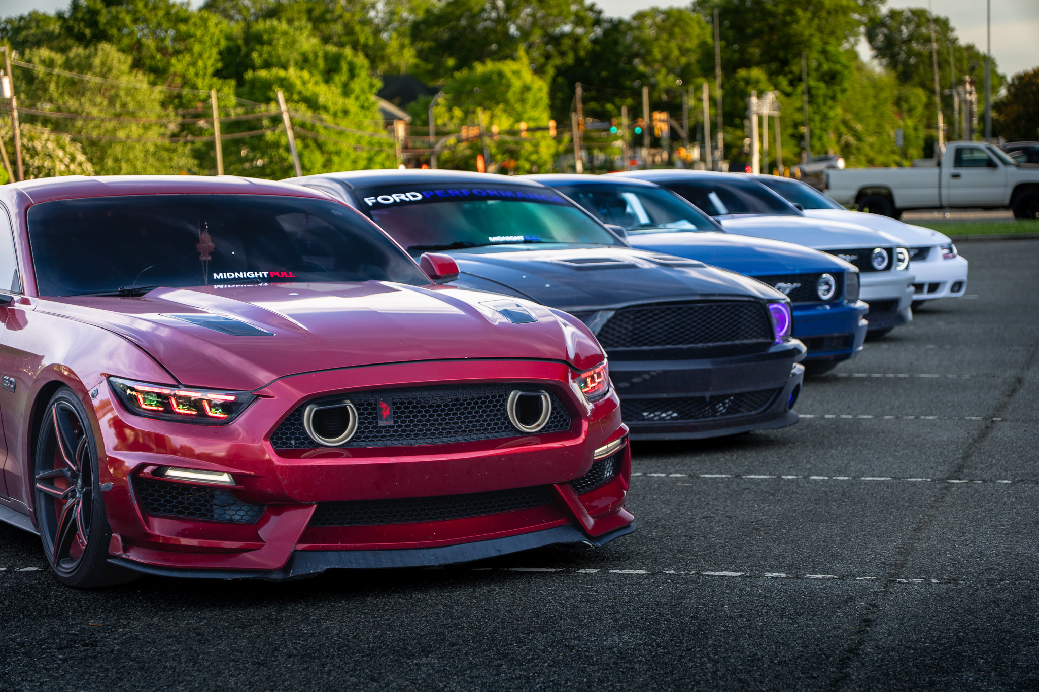 Six Ford Mustangs lined up at golden hour