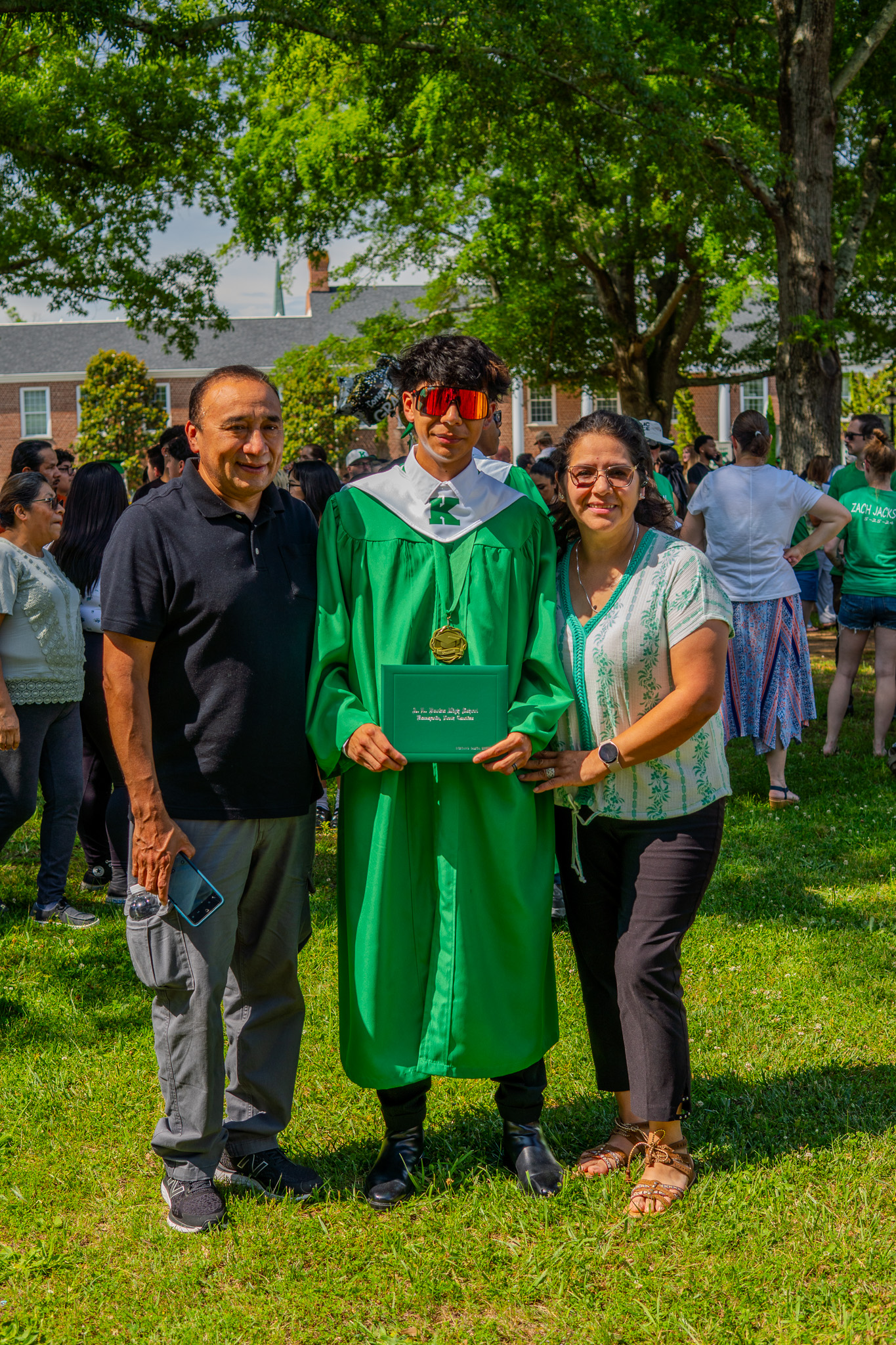 Graduate with family in cap and gown on campus lawn
