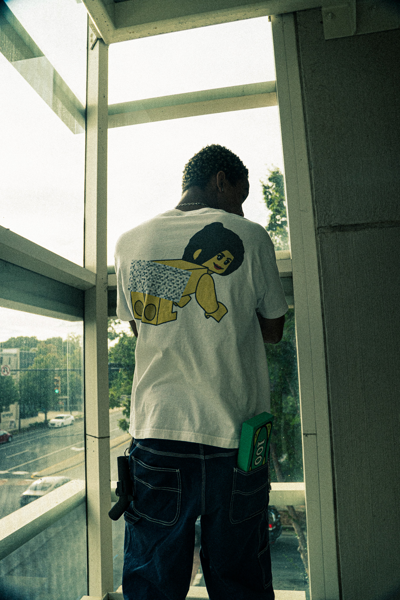 Model shot from behind wearing branded graphic tee on a balcony